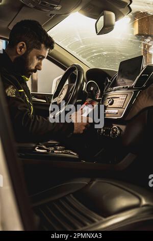 Mailand, Italien 11. april 2023: Die Hände eines Mechanikers verwenden ein Diagnosegerät, um Fehler am Computersystem eines modernen Autos in einer Garage zu beheben. Stockfoto