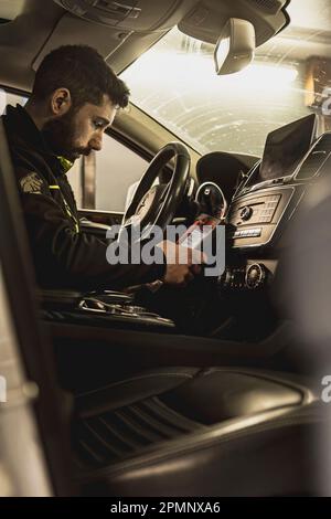 Mailand, Italien 11. april 2023: Die Hände eines Mechanikers verwenden ein Diagnosegerät, um Fehler am Computersystem eines modernen Autos in einer Garage zu beheben. Stockfoto
