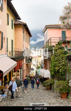 Touristen in einer engen Straße im Stadtzentrum von Bellagio mit Blick auf den Comer See, die Lombardei, Italien. Stockfoto