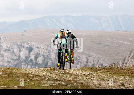 Zwei männliche Radfahrer, die auf einem Mountainbike in der Bergregion unterwegs sind. Rucksack auf der Rückseite des Mountainbikers Stockfoto