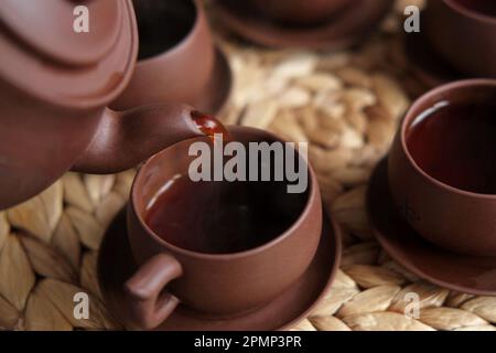 Teezeremonie. Traditionelles Asiatisches Teeutensil, Serviert Authentisches Set. Person, die Tee von der Teekanne aus brauner Keramik bis zur Teekanne einschenkt. Bambusschale. Lifestyle. Wir Stockfoto