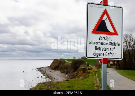 PRODUKTION - 13. April 2023, Schleswig-Holstein, Travemünde: Ein Schild mit der Aufschrift "Vorsicht, steile Ufer abbrechen, auf eigene Gefahr einfahren" steht am Brodtener Steilufenufer. (Zu dpa: Abbrechkante rückt näher - Haus Seeblick steht fest über der Ostsee) Foto: Frank Molter/dpa Stockfoto