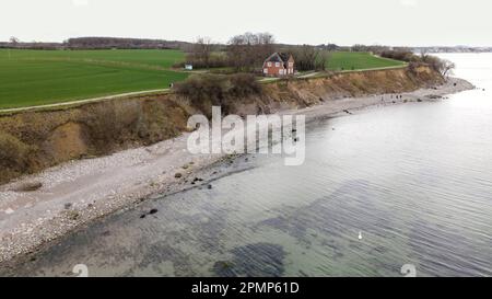 PRODUKTION - 13. April 2023, Schleswig-Holstein, Travemünde: Fußgänger gehen entlang der Brodtener Steilufer. (Luftfoto mit Drohne) der Rand des Brodtener Steilbeines nähert sich unaufhaltsam dem Haus „Seeblick“ der Jugendorganisation „Sozialistische Jugend Deutschlands – die Falken“. (Zu dpa: Abrisskante rückt näher - Haus Seeblick steht fest über der Ostsee) Foto: Frank Molter/dpa Stockfoto