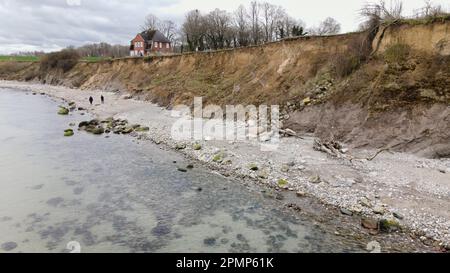 PRODUKTION - 13. April 2023, Schleswig-Holstein, Travemünde: Fußgänger gehen entlang der Brodtener Steilufer. (Luftfoto mit Drohne) der Rand des Brodtener Steilbeines nähert sich unaufhaltsam dem Haus „Seeblick“ der Jugendorganisation „Sozialistische Jugend Deutschlands – die Falken“. (Zu dpa: Abrisskante rückt näher - Haus Seeblick steht fest über der Ostsee) Foto: Frank Molter/dpa Stockfoto