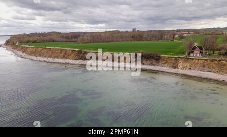 PRODUKTION - 13. April 2023, Schleswig-Holstein, Travemünde: Fußgänger gehen entlang der Brodtener Steilufer. (Luftfoto mit Drohne) der Rand des Brodtener Steilbeines nähert sich unaufhaltsam dem Haus „Seeblick“ der Jugendorganisation „Sozialistische Jugend Deutschlands – die Falken“. (Zu dpa: Abrisskante rückt näher - Haus Seeblick steht fest über der Ostsee) Foto: Frank Molter/dpa Stockfoto