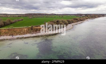 PRODUKTION - 13. April 2023, Schleswig-Holstein, Travemünde: Fußgänger gehen entlang der Brodtener Steilufer. (Luftfoto mit Drohne) der Rand des Brodtener Steilbeines nähert sich unaufhaltsam dem Haus „Seeblick“ der Jugendorganisation „Sozialistische Jugend Deutschlands – die Falken“. (Zu dpa: Abrisskante rückt näher - Haus Seeblick steht fest über der Ostsee) Foto: Frank Molter/dpa Stockfoto