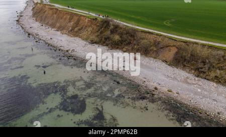 PRODUKTION - 13. April 2023, Schleswig-Holstein, Travemünde: Fußgänger gehen am Brodtener-Steilufenufer entlang. (Luftbild mit Drohne) (zu dpa: Abrisskante rückt näher - Haus Seeblick steht fest über der Ostsee) Foto: Frank Molter/dpa Stockfoto