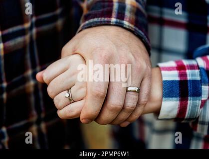 Nahaufnahme der Hände eines Mannes und einer Frau mit ihren Eheringen in Edmonton, Alberta, Kanada Stockfoto