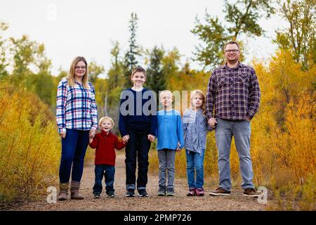 Eine sechsköpfige Familie, die im Herbst Hand in Hand in einem Park in Edmonton, Alberta, Kanada, steht Stockfoto