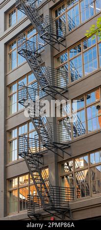 Die Feuertreppe wurde außerhalb des Western Building in Downtown Seattle, Washington, mit Reflexionen in den Fenstern montiert Stockfoto