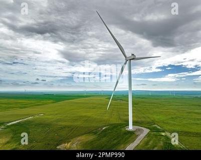 Große Windturbine in einer weitläufigen Landschaft und einem wolkigen Himmel im Nordosten von Waterton, Alberta, Kanada Stockfoto