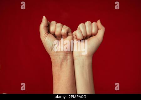 Die Menschen erhoben Luftkämpfe mit der Faust auf rotem Hintergrund, Wettkampf, Teamwork-Konzept, Hintergrundbereich für Text. Stockfoto