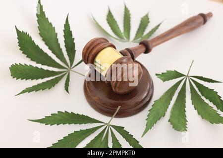 Der hölzerne Hammer des Richters liegt auf einem Schallblock von grünem Cannabis Stockfoto