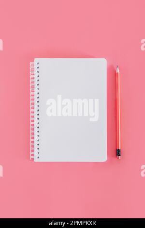 Notizbuch mit einer leeren Seite und einem Bleistift auf pinkfarbenem Hintergrund. Flach verlegt. Platz für Text. Stockfoto