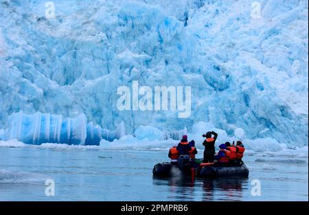 Gruppe von Ökotouristen in einem aufblasbaren Motorboot sehen eine ungewöhnliche Eisformation des South Sawyer Glacier in der Tracy Arm-Fords Terror Wilderness Area Stockfoto