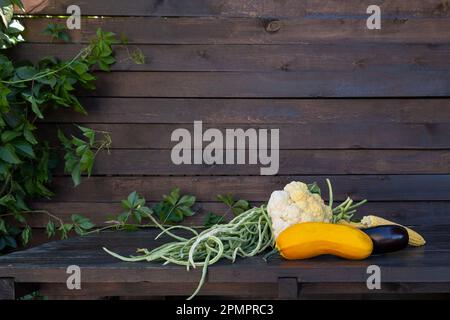 Bio-Gemüse auf einem dunklen Holztisch. Frischer roher Blumenkohl, grüne Bohnen, Zucchini, Mais, Rüben. Die Farm hat das Leben in der Natur gemessen Stockfoto