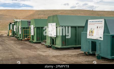 Fort Collins, CO, USA - 13. April 2023: Recyclingzentrum - eine Reihe grüner Stahlbehälter mit Hinweisschildern auf der Deponie von Larimer County. Stockfoto