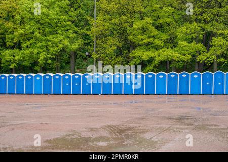 Eine Reihe tragbarer Toiletten vor einem Wald. Stockfoto