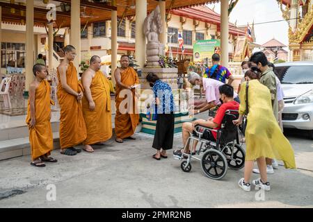 Pak Kret, Thailand. 14. April 2023. Eine thailändische Familie gibt dem Mönch Almosen, während des Songkran Festivals im Wat Sanam Nuea Tempel, in der Stadt Pak Kret, in der Provinz Nonthaburi. Das Songkran Festival ist ein traditionelles buddhistisches Festival, das den Beginn des thailändischen Neujahrs markiert. Zusätzlich zu traditionellen Wasserritualen und Straßenpartys gibt es weitere wichtige Aktivitäten, an denen die Thailänder in dieser Woche teilnehmen, um an traditionellen buddhistischen Ritualen teilzunehmen. Kredit: SOPA Images Limited/Alamy Live News Stockfoto