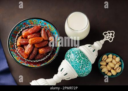 Ramadan Kareem – Speisen und Getränke. Datteln Sie Früchte, Nüsse und Milch auf dunklem Hintergrund. Das Ramadan-Karäm-Fasting-Monatskonzept. Draufsicht Stockfoto