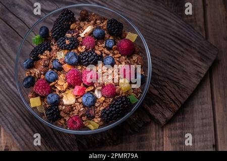 Große Glasschüssel mit Beeren und Müsli. Wunderschöne und saftige Waldbeeren. Müsli und Beeren auf dem Tisch. Blick von oben. Stockfoto