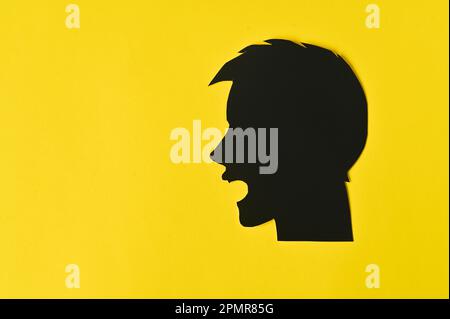 Der Begriff der psychologischen Hilfe. Der junge Mann ist sehr wütend und schreit. Die Silhouette des Kopfes. Stockfoto