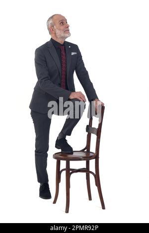 Der Blick auf einen stehenden Mann, der mit einem Stuhl im Anzug und einer Krawatte spielt, ist auf weißem Hintergrund Stockfoto