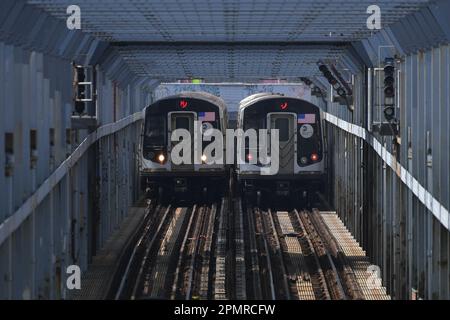 Zwei U-Bahnen überqueren die Williamsburg Bridge am 14. April 2023 in New York City. Stockfoto