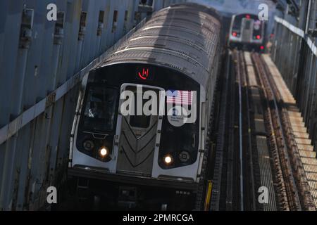 Zwei U-Bahnen überqueren die Williamsburg Bridge am 14. April 2023 in New York City. Stockfoto