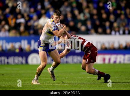 Warrington Wolves' Matty Nicholson (links) wird während des Spiels der Betfred Super League im Halliwell Jones Stadium, Warrington, von Harry Smith der Wigan Warriors angegriffen. Foto: Freitag, 14. April 2023. Stockfoto