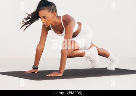 Fit Weibchen in weißer Fitnesskleidung, die Kernübungen auf einer Matte macht. Schlanke Frau, die intensives Workout im Freien macht. Stockfoto