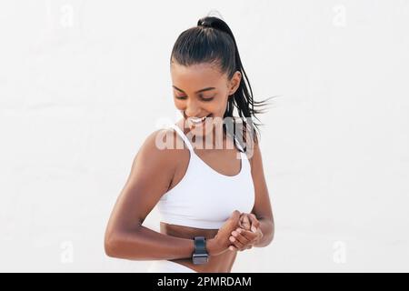 Glückliche Frau, die ihren Bizeps ansieht. Junge Frau, die fit ist und ihre Muskeln am Arm zeigt. Stockfoto