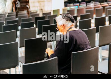 Ältere Frau, die auf einem Kirchenstuhl sitzt. St. Bavos Kathedrale, innen. Gent, Ostflandern, Flämische Region, Belgien, Europa Stockfoto