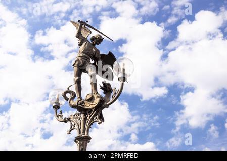 Lampenpfosten mit einer Bronzeskulptur des Erzengels Michael, auch bekannt als St. Michael, mit einem besiegten Drachen zu seinen Füßen. St. Michael Brücke. Das br Stockfoto