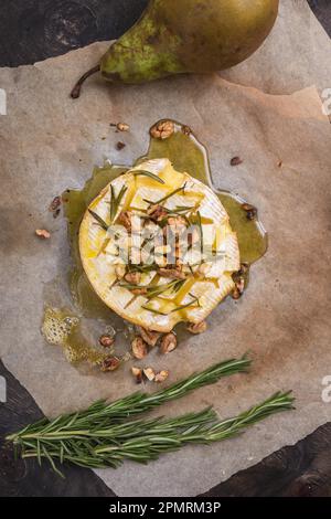 Köstlicher, wunderschöner gebackener Camembert mit Honig, Walnüssen, Kräutern und Birnen Stockfoto