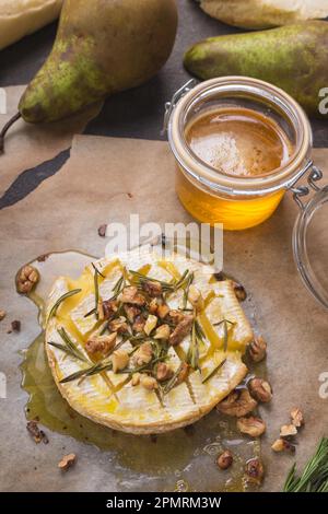 Köstlicher, wunderschöner gebackener Camembert mit Honig, Walnüssen, Kräutern und Birnen Stockfoto
