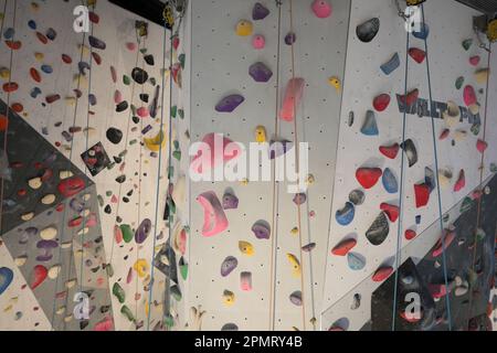 Künstliche Kletterwand mit bunten Steinen. Stockfoto