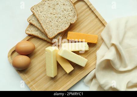 Käse, Ei und Brot auf Holzteller über dem Tisch Stockfoto
