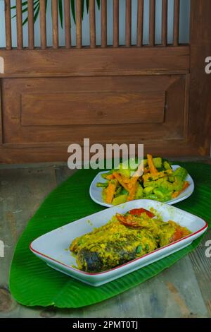 Pesmol ikan oder Acar ikan Kuning ist ein Fischgericht aus Gourami, Makrele, Tilapia oder Papageienfisch, gekocht in Kurkumasoße mit Gewürzen. Serviert mit verschiedenen Stockfoto