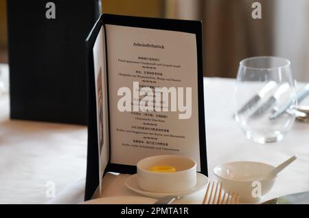 Peking, China. 15. April 2023. Vor einem Arbeitsfrühstück des deutschen Außenministers Baerbock (Bündnis 90/die Grünen) und Politbüro-Mitglieds Wang in der Großen Halle des Hotel St. Regis Bejing, eine Speisekarte auf Deutsch und Chinesisch, steht neben dem Platz des deutschen Politikers. Kredit: Soeren Stache/dpa/Alamy Live News Stockfoto