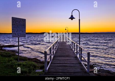 Sonnenuntergang über dem Horizont über dem Lake Macquarie vom Holzfischersteg in Murrays Beach - australische Landschaft. Stockfoto