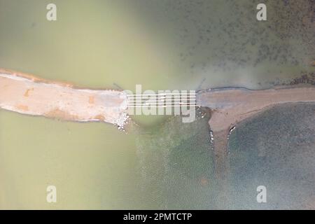 PRODUKTION - 13. April 2023, Hessen, Bad Soden-Salmünster: Die Überreste einer Baubrücke, die bei einem Winterhochwasser zerstört wurde, sind im Reservoir der Kinzigtalsperre zu sehen. (Drohnenschuss) seit Mitte 2022 wurde diese aufgrund einer alle 20 Jahre stattfindenden Sicherheitsinspektion teilweise geleert. (Zu dpa 'die Arbeit an der Kinzigtalsperre geht nach den Winterferien weiter') Foto: Sebastian Gollnow/dpa Stockfoto