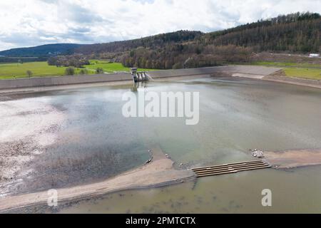 PRODUKTION - 13. April 2023, Hessen, Bad Soden-Salmünster: Die Überreste einer Baubrücke, die bei einem Winterhochwasser zerstört wurde, sind im Reservoir der Kinzigtalsperre zu sehen. (Drohnenschuss) seit Mitte 2022 wurde diese aufgrund einer alle 20 Jahre stattfindenden Sicherheitsinspektion teilweise geleert. (Zu dpa 'die Arbeit an der Kinzigtalsperre geht nach den Winterferien weiter') Foto: Sebastian Gollnow/dpa Stockfoto