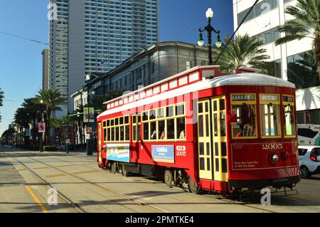 Eine historische rote Straßenbahn fährt durch die Innenstadt von New Orleans entlang der Canal Street und stellt öffentliche Verkehrsmittel für die Stadt bereit Stockfoto