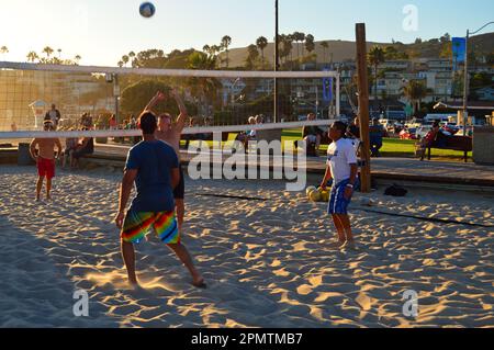 Eine Gruppe junger erwachsener Freunde spielt Beachvolleyball und spielt auf dem Sand in Laguna Beach, Kalifornien Stockfoto