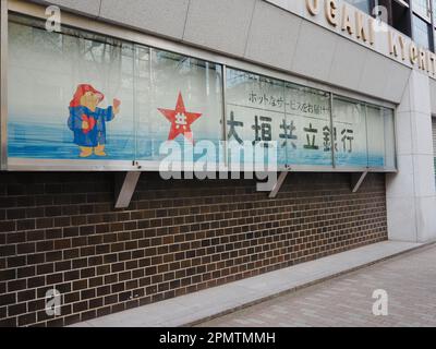 TOKIO, JAPAN - 6. April 2023: Anzeigefenster an der Seite einer Zweigstelle der Ogaki Kyoritsu Bank in Tokios Bereich Hachobori. Hier ist Paddington Bear. Stockfoto