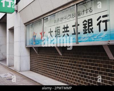 TOKIO, JAPAN - 6. April 2023: Anzeigefenster an der Seite einer Zweigstelle der Ogaki Kyoritsu Bank in Tokios Bereich Hachobori. Hier ist Paddington Bear. Stockfoto