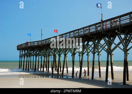Ein hölzerner Pier erstreckt sich in den Ozean entlang der Küste und der Küste von Myrtle Beach Stockfoto