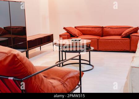 Rotbraunes weiches Sofa mit Kissen im Zimmer und runder Couchtisch. Stockfoto