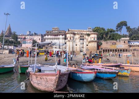 Varanasi, Uttar Pradesh, Indien - November 2022: Ein Blick auf die heiligen Ghats von Varanasi mit einem Bootsmann, der auf dem Boot in der Nähe des Ufers des ganges steht. Stockfoto